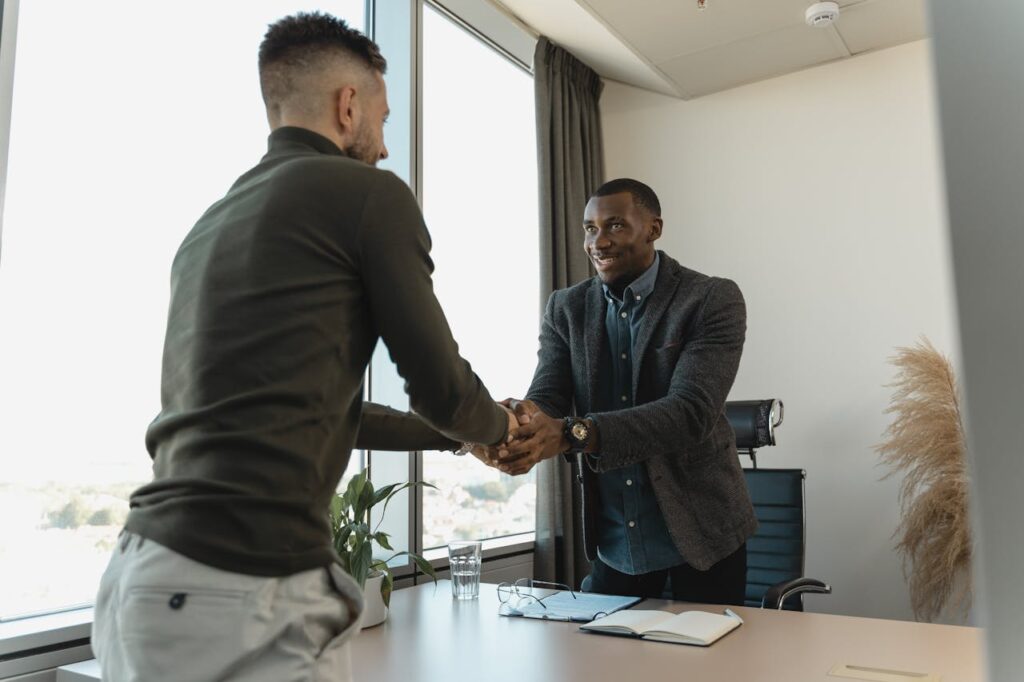 Two businessmen exchanging a handshake during a professional meeting in a modern office setting.